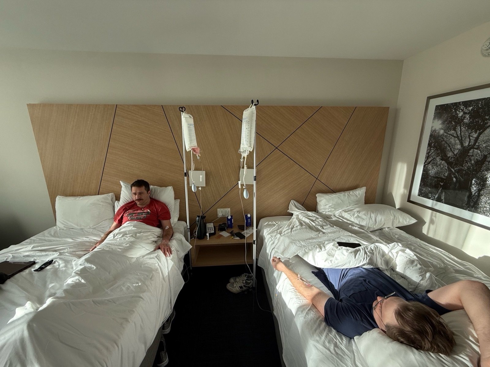 Two clients receiving IV hydration in a hotel room