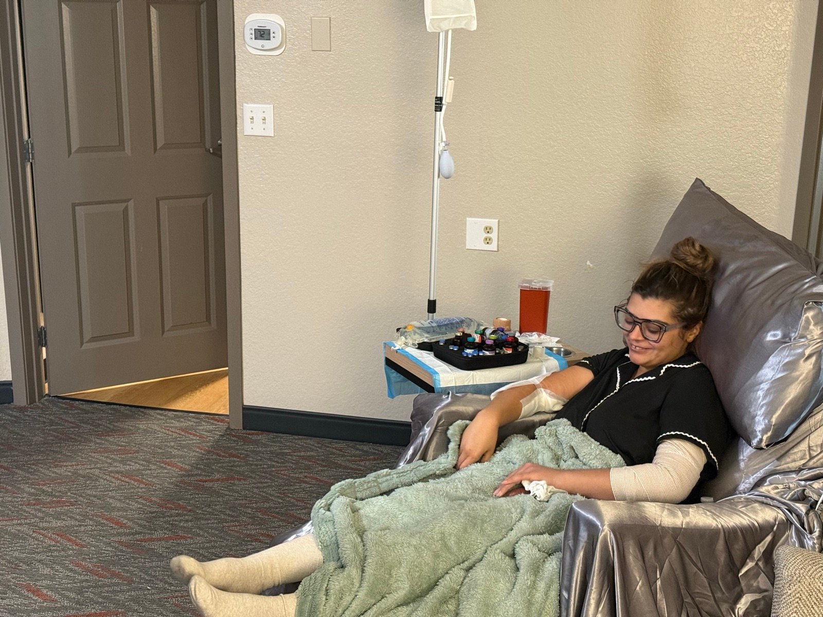 A client resting in a recovery chair with an IV drip